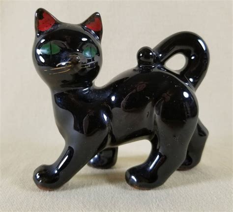 A Black Cat Figurine Sitting On Top Of A Table