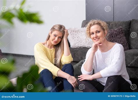 Two Woman Sit Next To Each Other And Look At The Camera Symbolizing