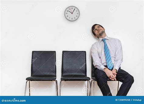 Tired And Exhausted Man Is Sitting In Waiting Room On Chair Stock