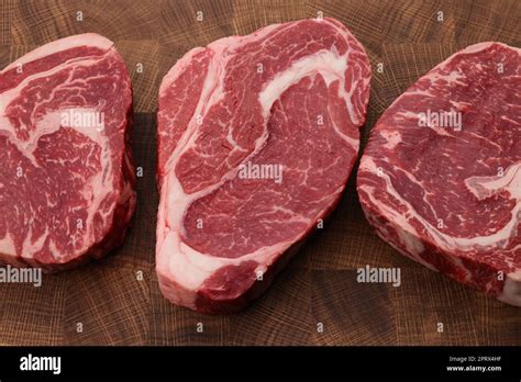 Three Raw Ribeye Beef Steaks On Cutting Board Stock Photo Alamy