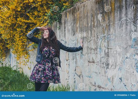 Pretty Girl With Long Hair Leaning Against A Concrete Wall Stock Photo