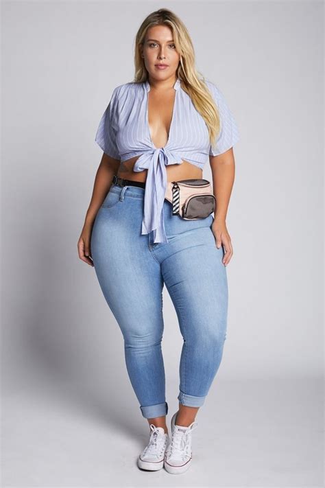 A Woman In High Waist Jeans And A Blue Shirt Is Posing For The Camera