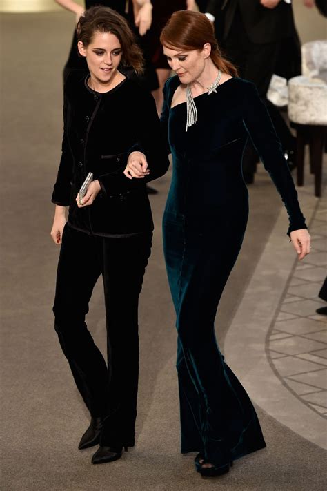 Two Women In Black Dresses Walking Down The Runway