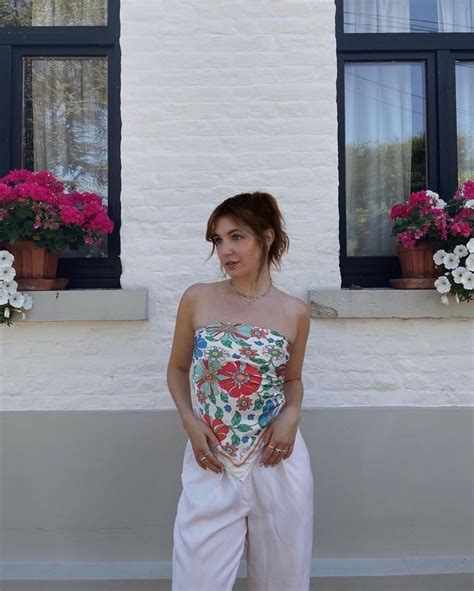 A Woman Is Standing In Front Of Some Flowers