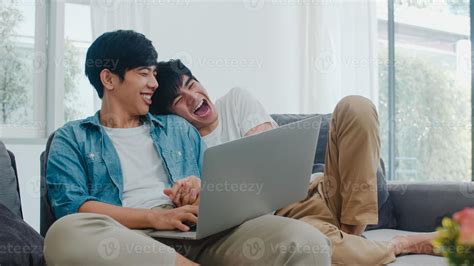 joven pareja gay con ordenador portátil en casa moderna Los hombres asiáticos lgbtq felices se