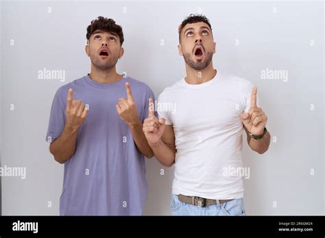 Homosexual Gay Couple Standing Over White Background Amazed And Surprised Looking Up And
