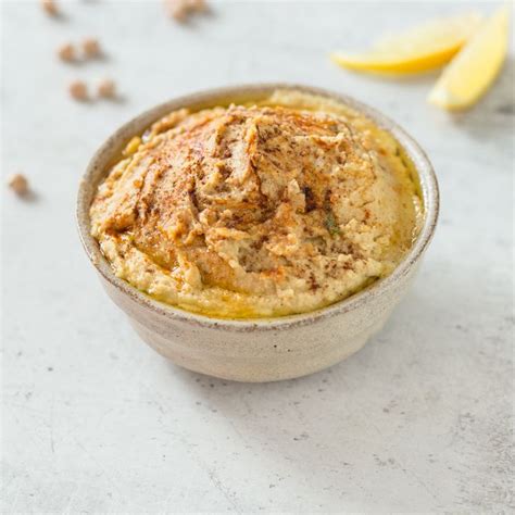 A Bowl Filled With Food Sitting On Top Of A White Counter Next To Lemon