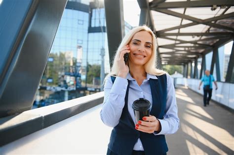 Hermosa mujer yendo a trabajar con café caminando cerca del edificio de