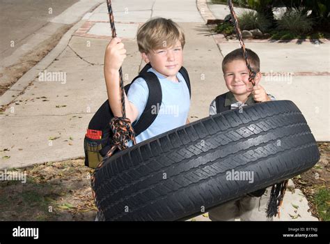 Two kids play on a tire swing after school Stock Photo - Alamy