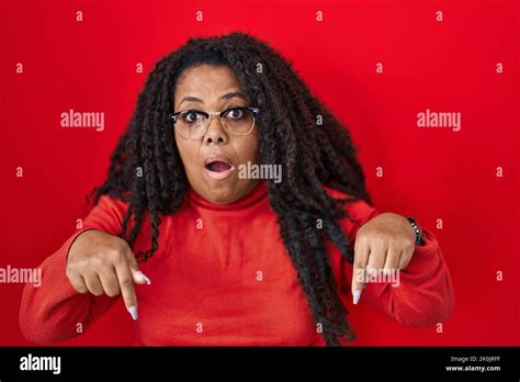 Plus Size Hispanic Woman Standing Over Red Background Pointing Down With Fingers Showing