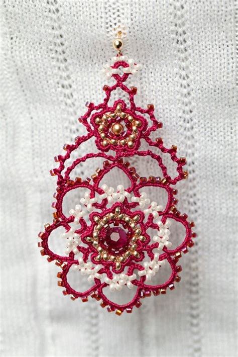 A Red And White Beaded Broochle Hanging From A Hook On A Piece Of Fabric