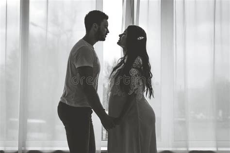 A Pregnant Girl With Her Husband Are Standing In A Bright Bedroom