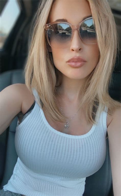 The Allie Rae Wearing Big Sunglasses With Blonde Highlighted Hair And White Ribbed Tank Top Big