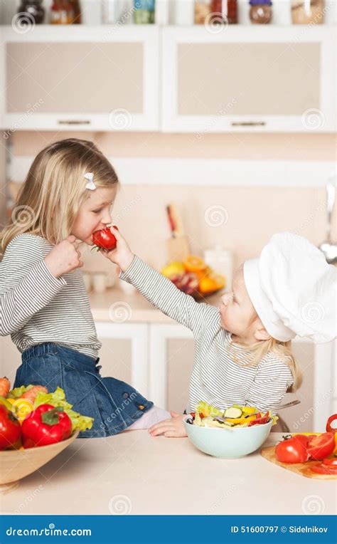 Petite Fille Alimentant Sa Tomate De Soeur Tandis Que Image Stock