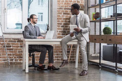 Handsome Businessman Sitting At Table And Looking At African American