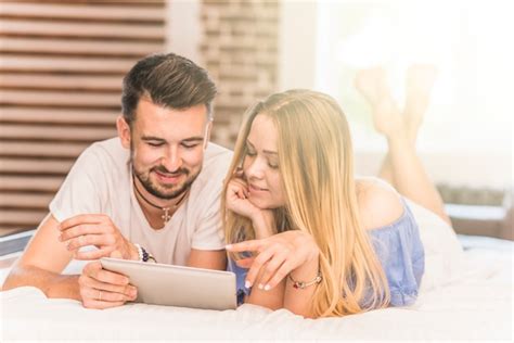 Jeune Couple Allongé Sur Un Lit Douillet En Regardant Tablette