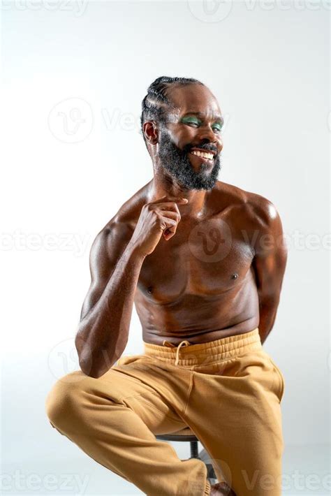 Happy Black Shirtless Gay Model Sitting On Stool In White Studio