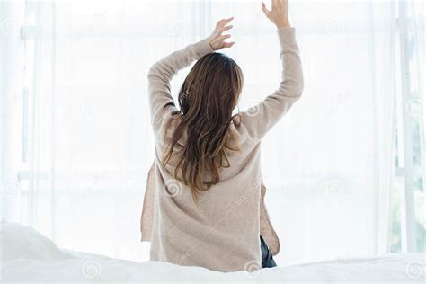 Back View Of Happy Beautiful Young Asian Woman Waking Up In Morning Sitting On Bed Stretching