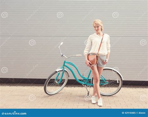Beautiful Blonde Girl Is Standing Near The Vintage Bicycle With Brown Vintage Bag Have Fun And