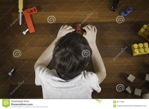 Top View Of Little Boy Lying On The Wooden Floor And Playing With