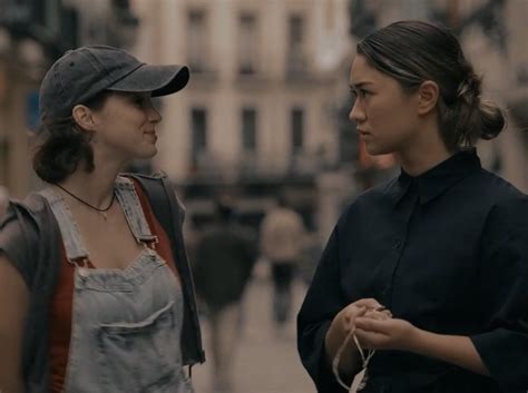 Two Women Standing Next To Each Other On A City Street