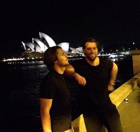 Two Men Standing Next To Each Other In Front Of The Sydney Opera House