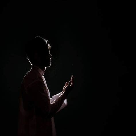 A Man Standing In The Dark With His Hands Folded Out And Looking Up At