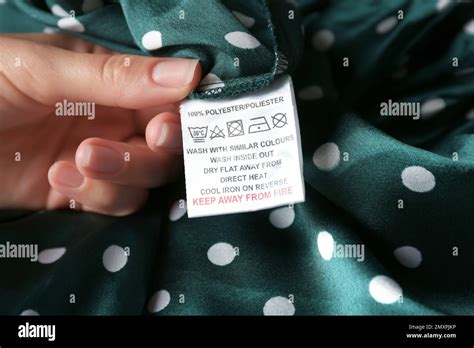 Woman Reading Clothing Label With Care Instructions And Content Information On Green Polka Dot