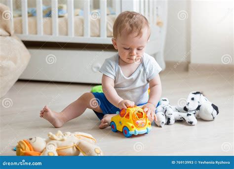 Adorable Baby Boy Playing With Toy Car On Floor At Living Room Stock