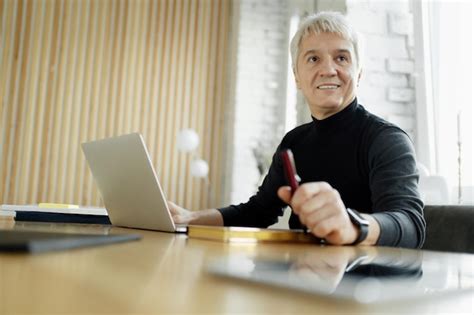 Premium Photo Mature Businessman With A Laptop And Phone In A Modern Office Looking Confident