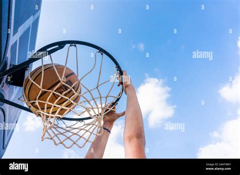 Young Boy Making A Slam Dunk In Street Basketball With Blue Sky And