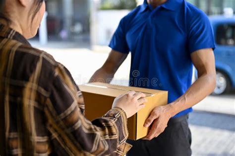 Cropped Short Of Delivery Man Wearing Blue Uniform Handing Parcel To