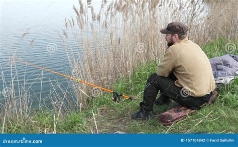 Un Pescatore Siede E Pesca Sulla Riva Uomo Che Aspetta Un Pesce Con