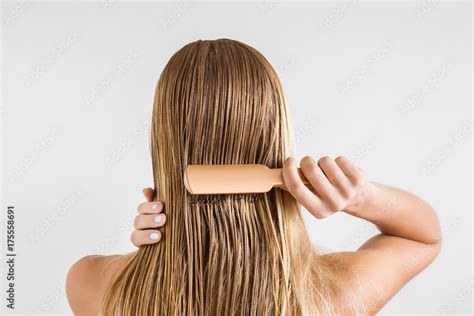 Woman With Comb Brushing Her Wet Blonde Hair After Shower On The Gray