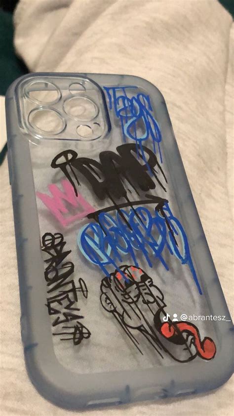 An Iphone Case With Graffiti On It Sitting On Top Of A White Sheet Covered Bed