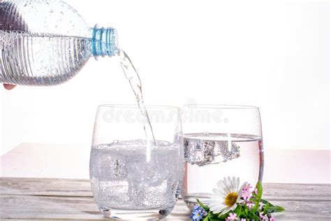 Pouring Of Sparkling Soda Mineral Drink Water In Glasses With Ice Cubes