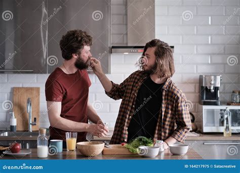 Two Men Tasting Food Together In The Kitchen Stock Image Image Of