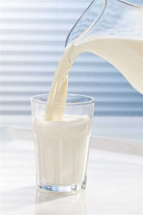 Milk Being Poured Into Glass Against White Background Stock Image