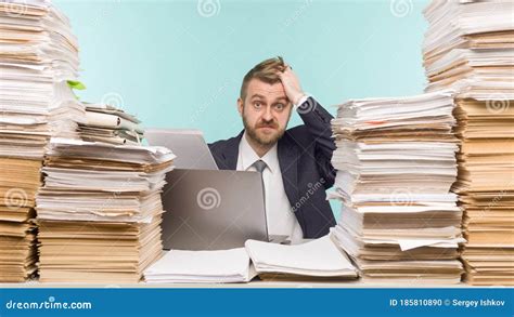 Shocked Businessman Sitting At The Table With Many Papers In Office