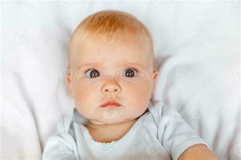 Cute Little Newborn Girl With Funny Face Looking At Camera On White