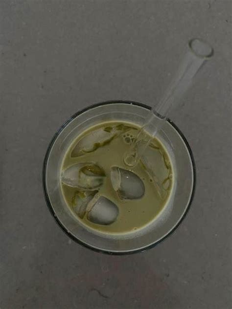 A Cup Filled With Liquid And Spoons On Top Of A Gray Table Next To A