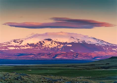 Colorida montaña volcánica con nube de casquete entre las tierras altas