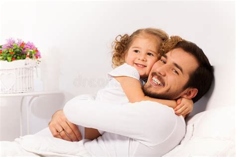 O Pai E a Filha De Sorriso Abraçam Na Cama Branca Imagem de Stock