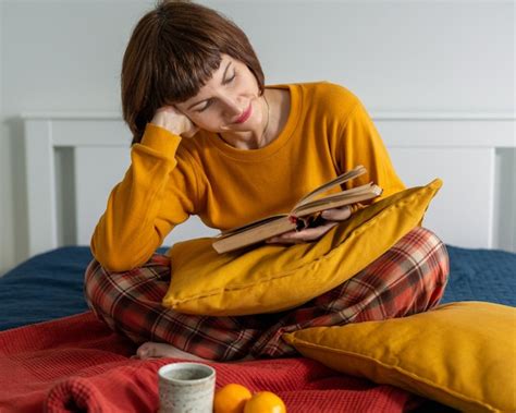 Premium Photo Smiling Woman Reading Book While Sitting On Bed At Home