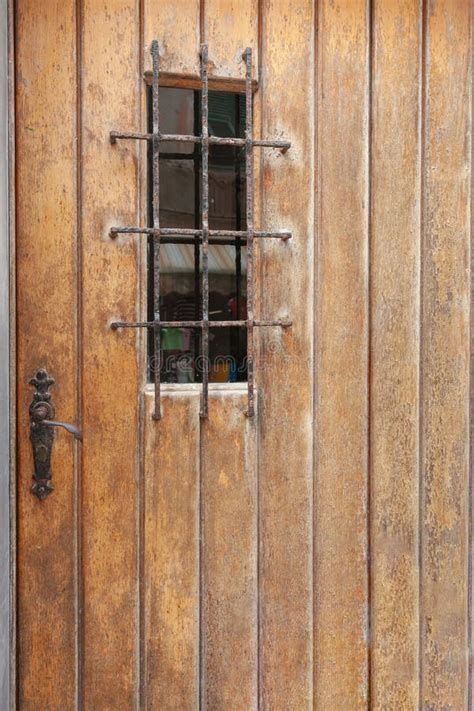 Rustic Wooden Door With Rusty Handle And Security Grille Stock Photo