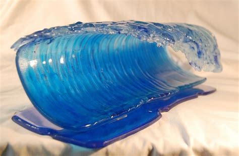 A Blue Glass Wave Sculpture Sitting On Top Of A White Sheet