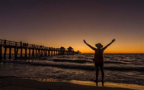 Premium Photo A Woman Stands On The Beach In Front Of A Pier With The