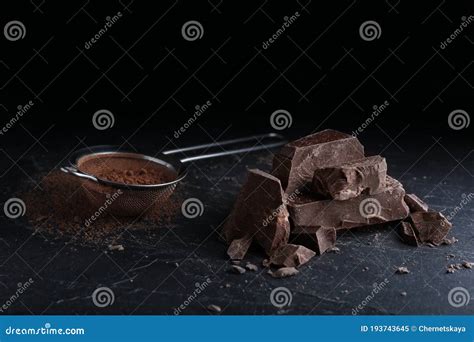 Pieces Of Dark Chocolate And Sieve With Cocoa Powder On Table Stock