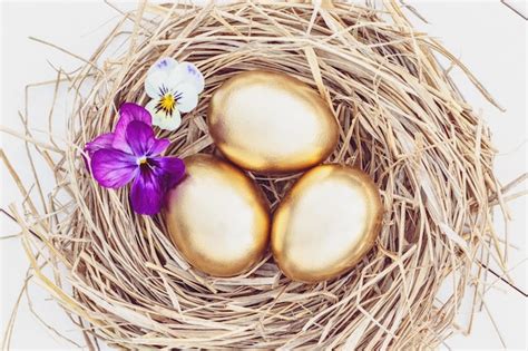 Premium Photo Easter Golden Eggs In A Hay Nest With Flowers Overhead