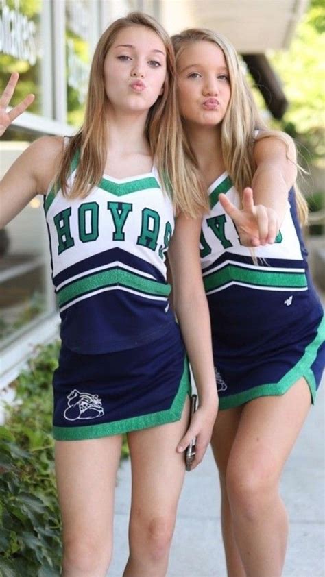 Two Young Women Dressed In Cheerleader Outfits Giving The Peace Sign